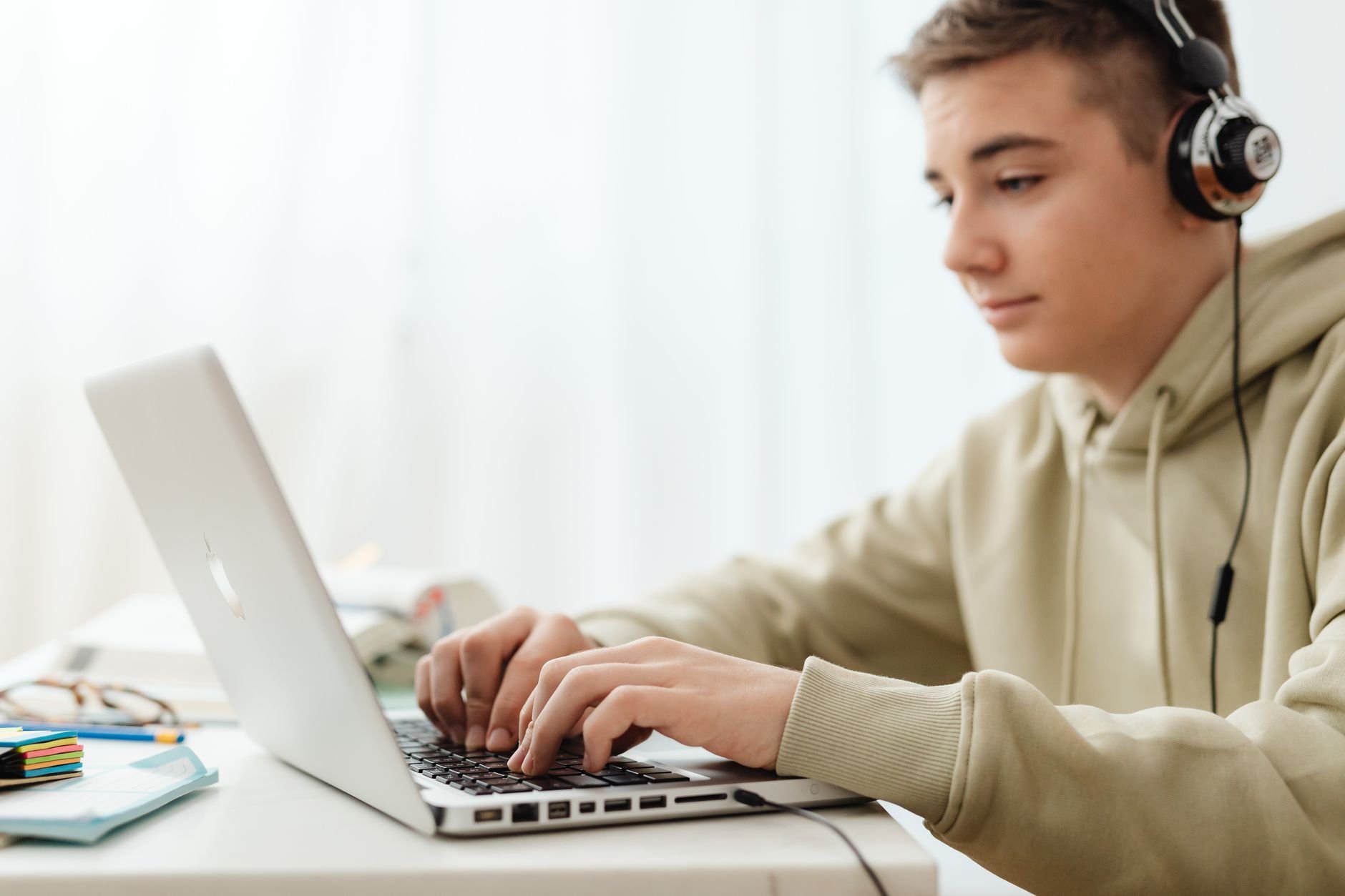 Teen using a laptop and headphones for online learning at home.