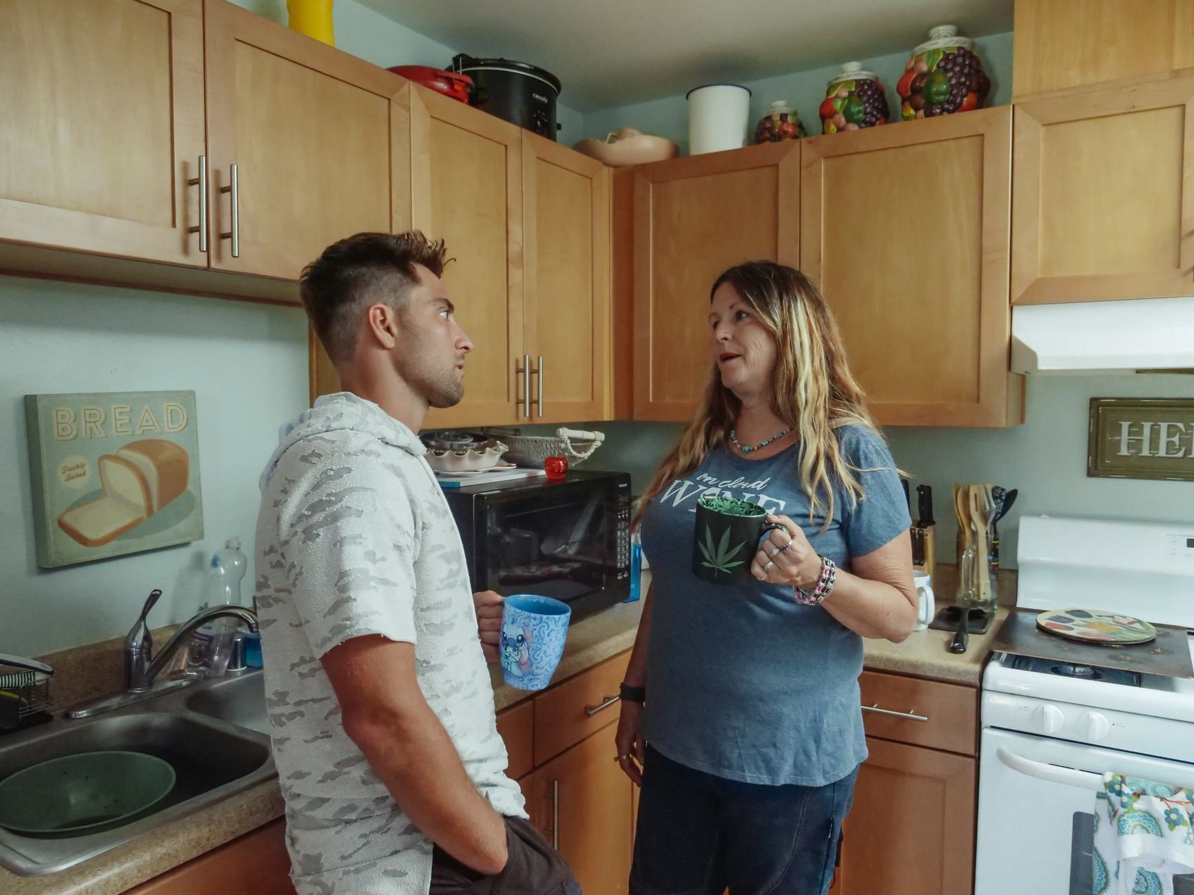 Mother and son having a serious conversation in the kitchen over coffee.